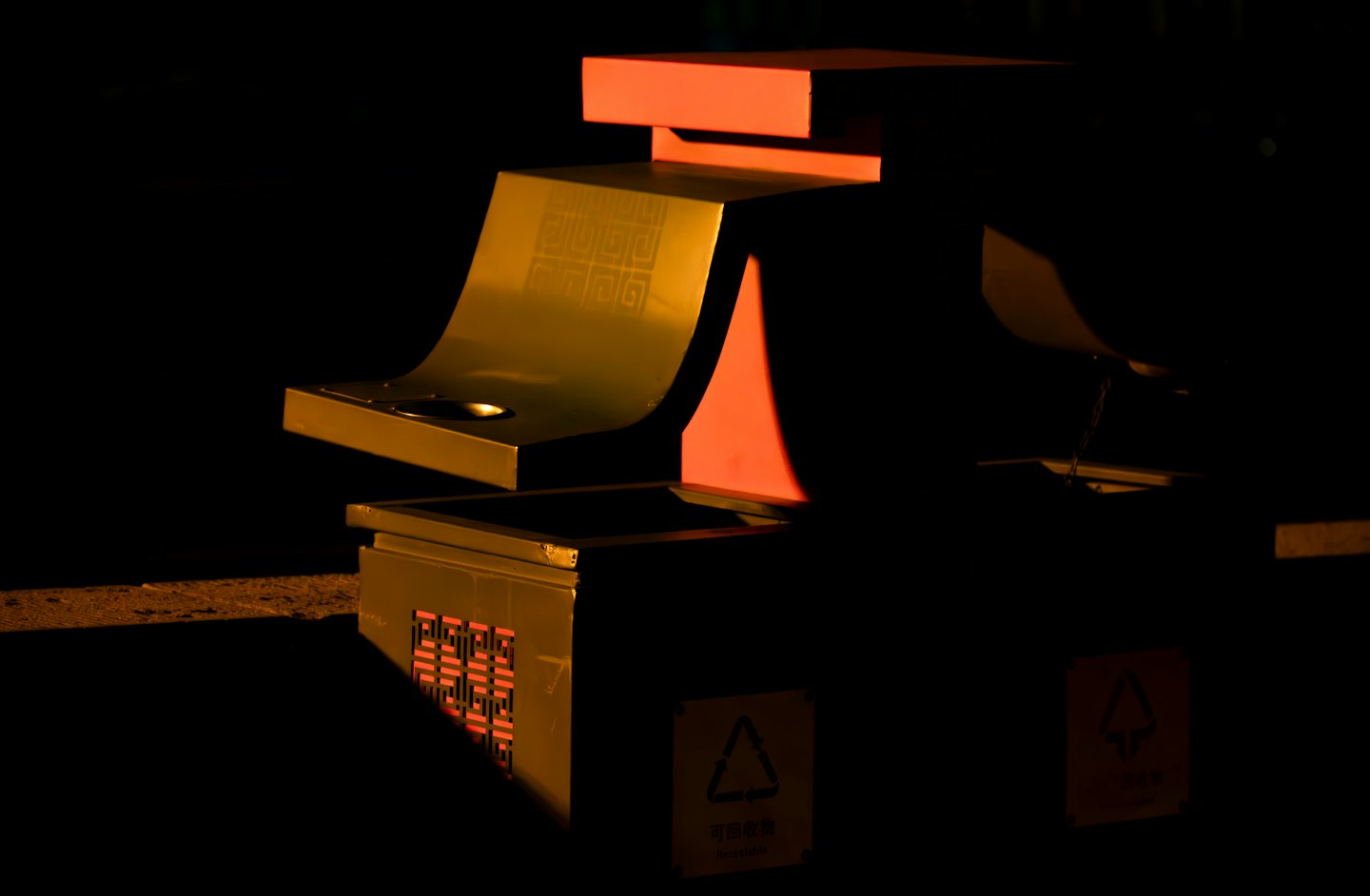 Modern metallic recycling station with bold red accents.